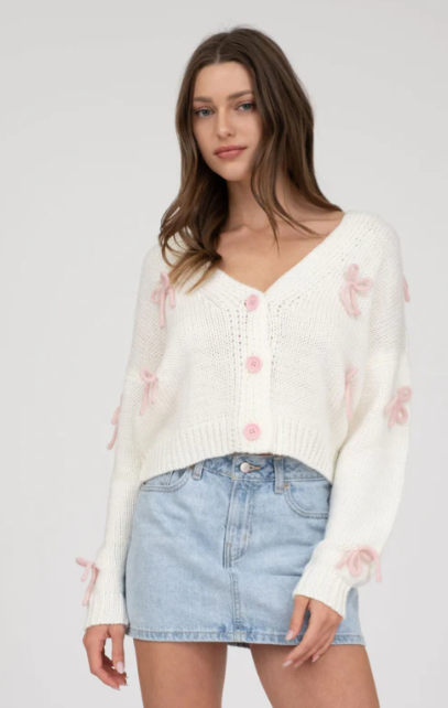 Cropped knit cardigan with pink bow details and button-down design.