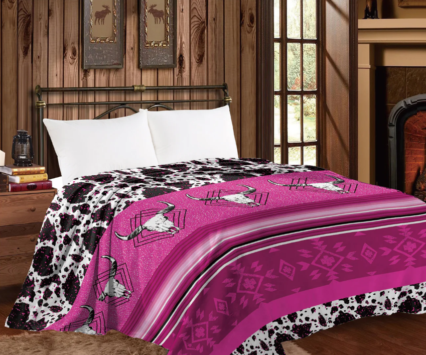 Mia Throw Blanket with pink longhorn skulls and cow print design on a bed.