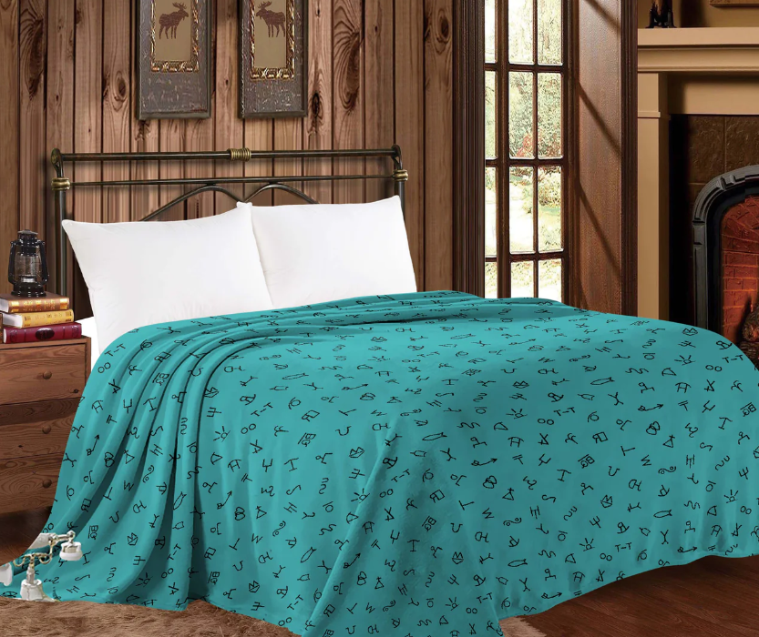 Mia Throw Blanket in Western Turquoise on a bed, showcasing stylish conchos and cowboy-themed design.