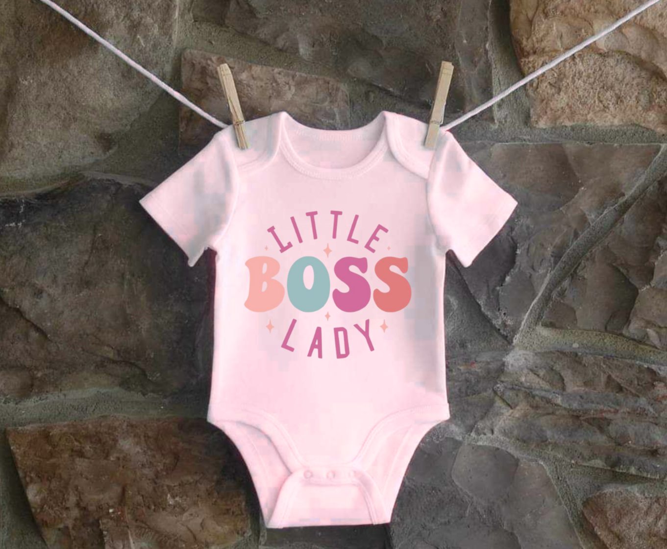 Infant bodysuit with "Little Boss Lady" text hanging on a clothesline.