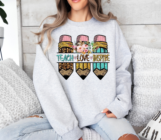 Teach Love Inspire sweatshirt, Gildan brand, featuring colorful pencil design with floral accents.