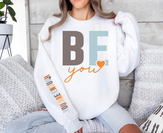 White sweatshirt with "Be You, You Are Enough" text and heart design.