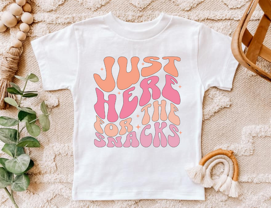 Infant and toddler pink snacks shirt with playful text design.