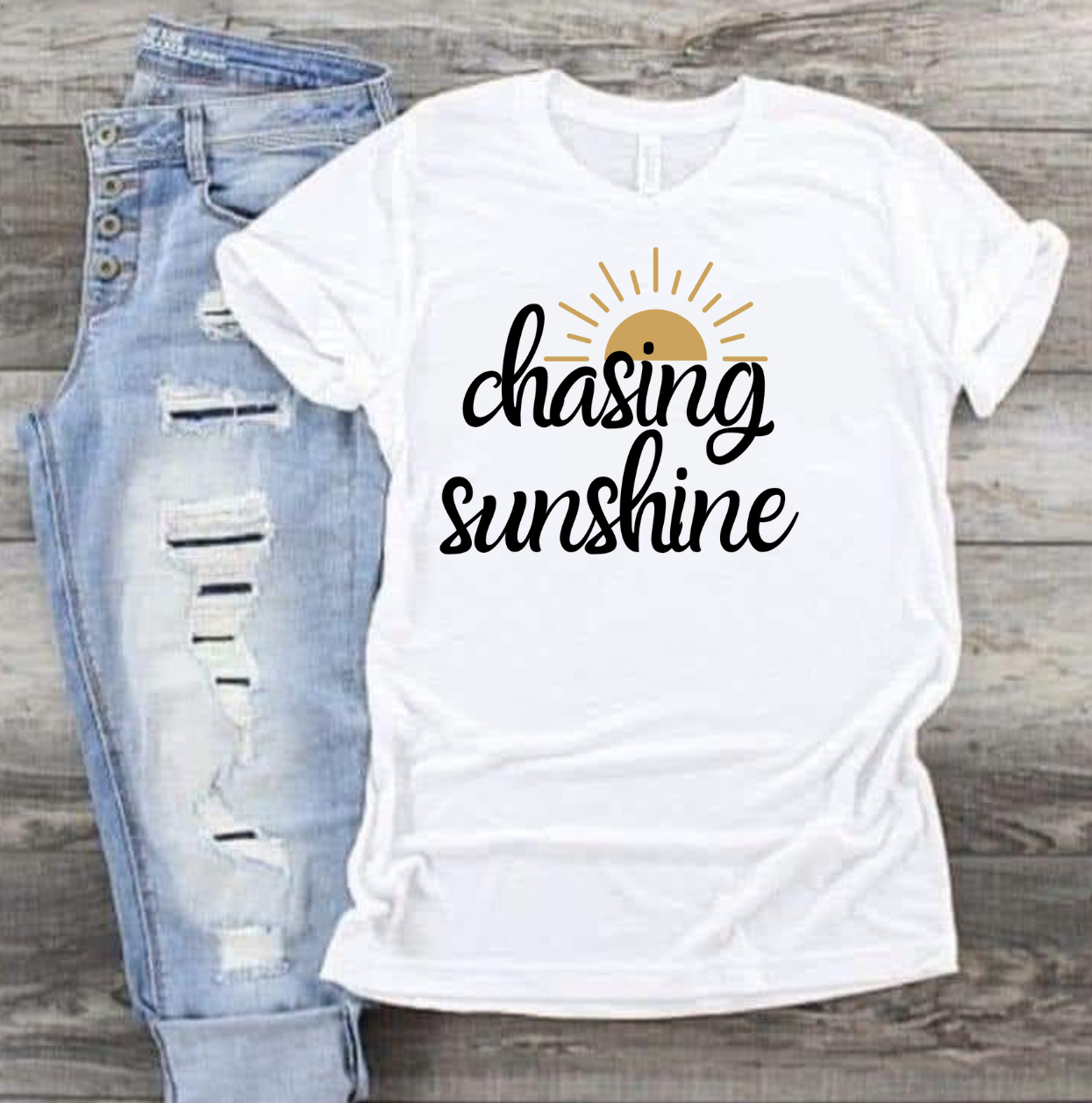 Chasing Sunshine T-shirt with sun graphic on white fabric, paired with distressed jeans.