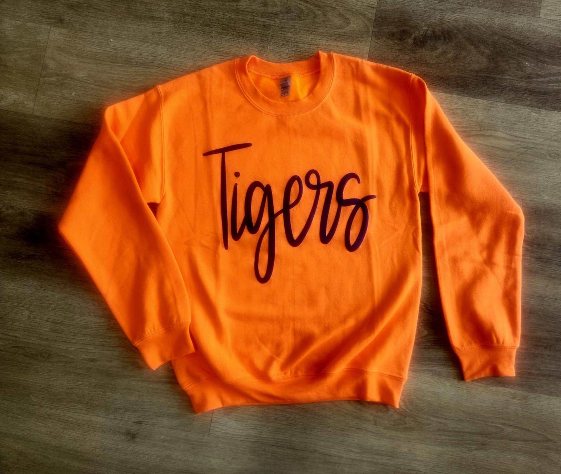 Orange Tigers Jumbo Puff Sweatshirt with black script text on wooden floor background