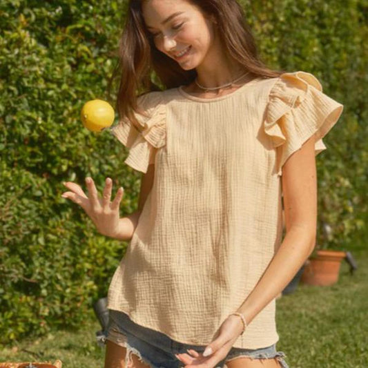 Short ruffle sleeve tunic blouse with a relaxed fit, worn by a woman outdoors.