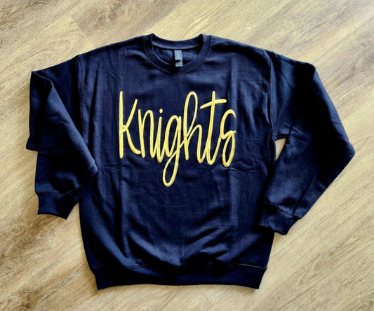 Black oversized Knights Jumbo Puff Sweatshirt with metallic gold "Knights" print on front.