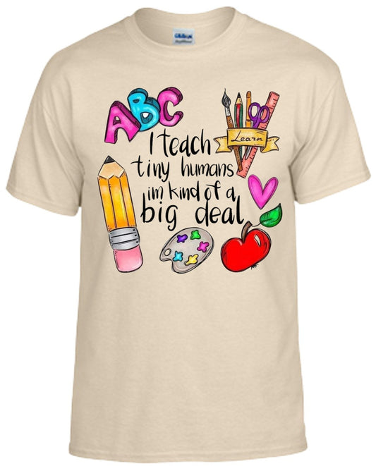 Shirt with "I Teach Tiny Humans I'm Kind of a Big Deal" design featuring colorful school-themed graphics.