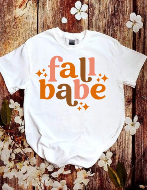 Youth Fall Babe shirt with autumn-themed design on wooden background.