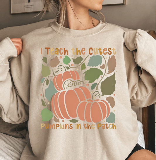 Teacher wearing "I Teach The Cutest Pumpkins In The Patch" shirt with playful pumpkin design.