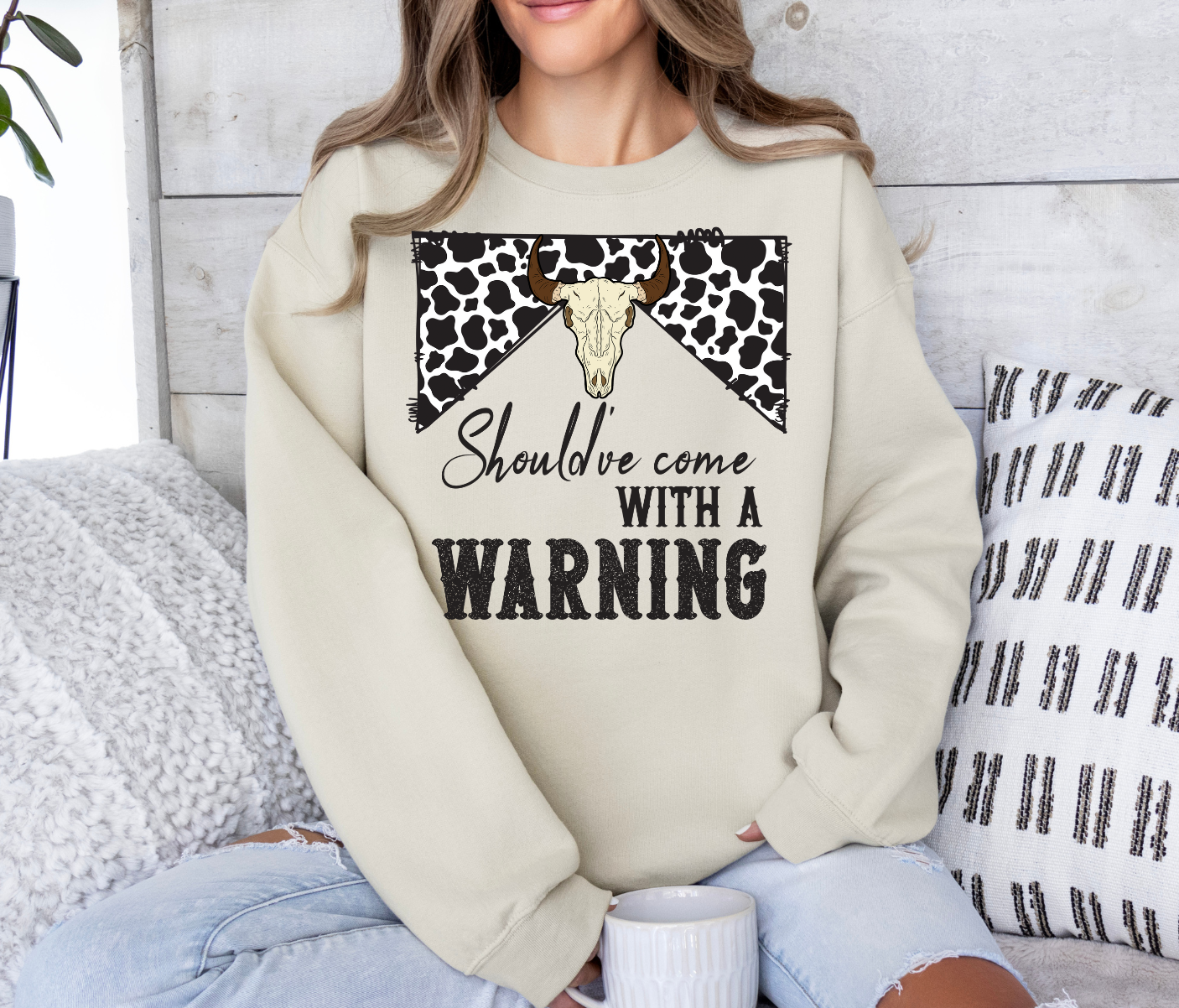 Fun shirt with "Should've Come With a Warning" design, beige sweatshirt with cow print and bull skull graphic.