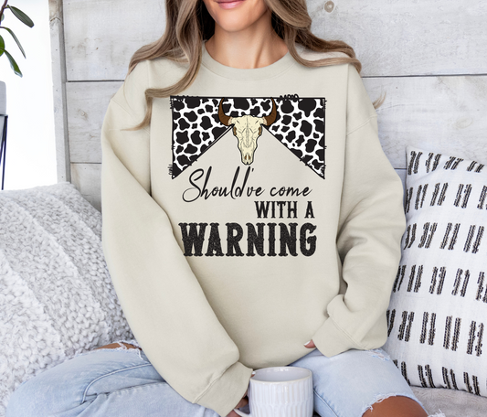 Fun shirt with "Should've Come With a Warning" design, beige sweatshirt with cow print and bull skull graphic.