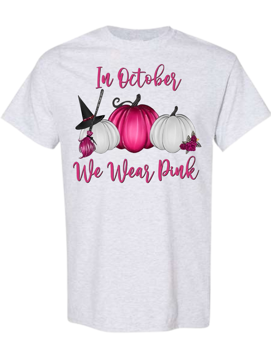 Pink pumpkin-themed t-shirt promoting breast cancer awareness with "In October We Wear Pink" message.