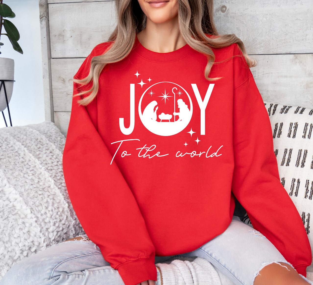 Red "Joy To The World" holiday shirt with festive lettering and nativity scene.