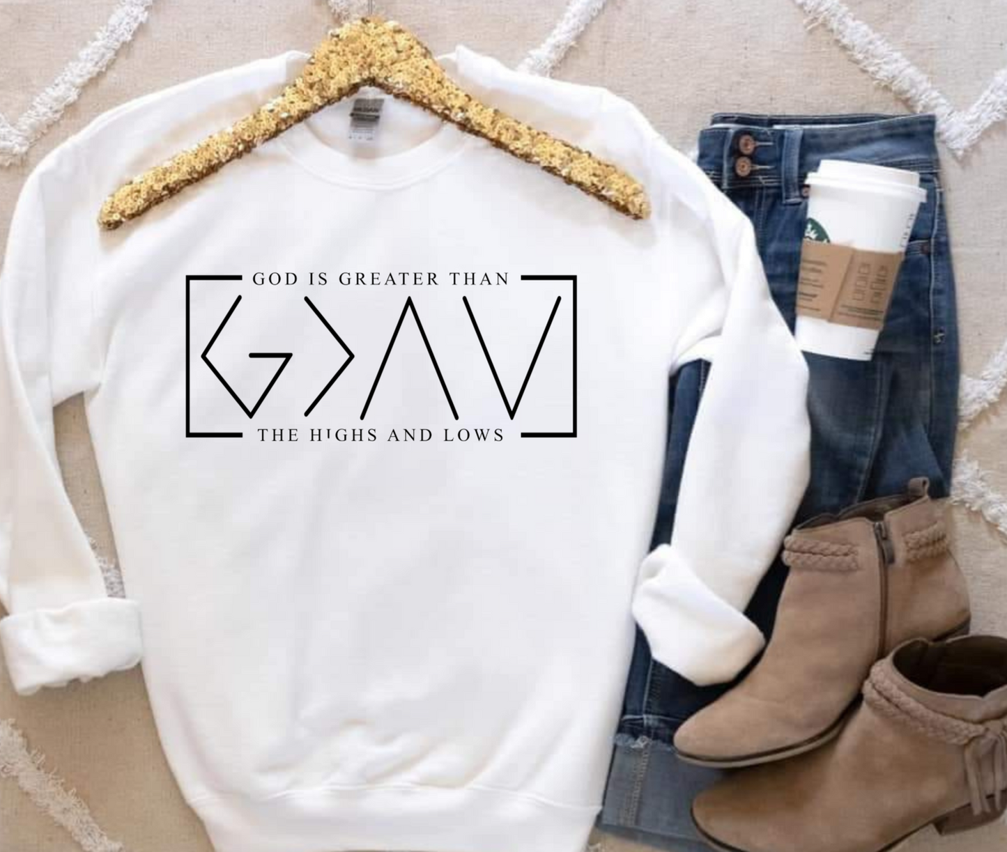 White Gildan sweatshirt with "God is Greater Than the Highs and Lows" text, styled with jeans and boots.
