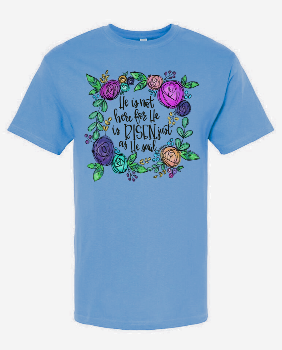 Christian blue T-shirt design featuring "He Is Not Here For He is Risen" text with colorful floral pattern.