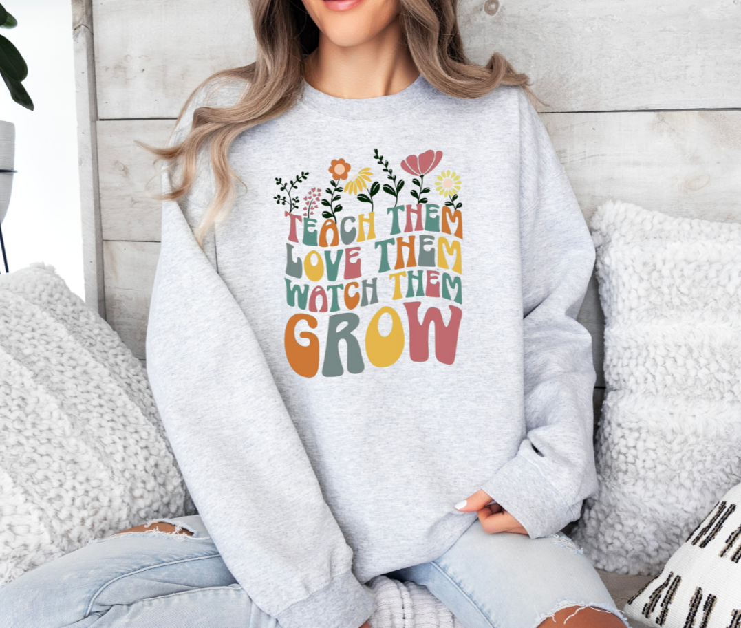 Sweatshirt with 'Teach Them Love Them Watch Them Grow' design, Gildan brand, 50/50 blend or 100% cotton.