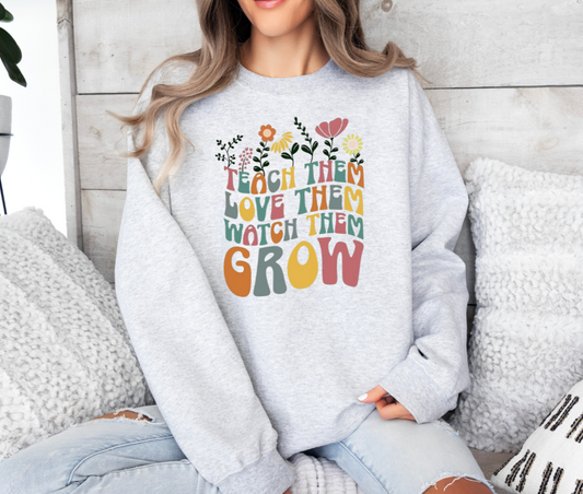 Sweatshirt with 'Teach Them Love Them Watch Them Grow' design, Gildan brand, 50/50 blend or 100% cotton.