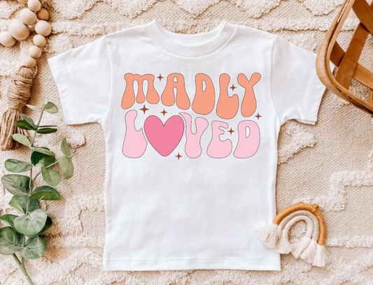 Madly Loved Pink infant and toddler shirt on textured background.