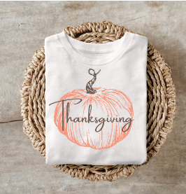 Thanksgiving pumpkin shirt folded on a woven basket.